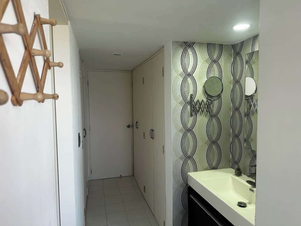 Une salle de bain avec un lavabo blanc, un miroir et un papier peint à motifs.