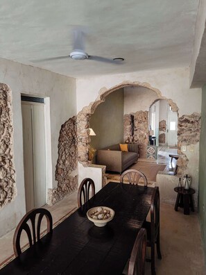 A dining area with a black table, chairs, and a bowl of snacks. There is a sofa and a lamp in the background. - Casa Saastal Colonial Home with Private Pool Merida (Merida)