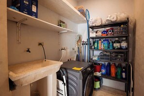 A laundry area with a washing machine, shelves with cleaning supplies, and a sink. - Colonial Mérida Retreat w/ Private Pool & Parking (Merida)