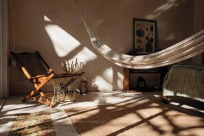 A room with a hammock, a wooden chair, a small table with a plant, and a bed. - Casa Saastal Colonial Home with Private Pool Merida (Merida)