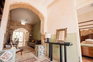 A room with a stone archway, a sofa, a table with a lamp, and a bed with a headboard. - Colonial Mérida Retreat w/ Private Pool & Parking (Merida)