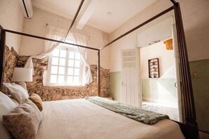 A bedroom with a four-poster bed, stone wall, and a window with curtains. - Colonial Mérida Retreat w/ Private Pool & Parking (Merida)