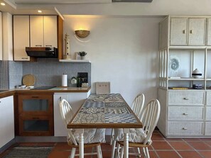 A compact kitchen with a tiled backsplash, a wooden countertop, and a dining table with chairs. - Cozy apartment | Playa Moreno | The Beach House (Pampatar)