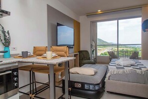 A modern hotel room with a balcony, a flat-screen TV, a dining area, and a bed. - Santa Marta Vista Mar Playa Privada (Santa Marta)