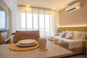 A hotel room with a bed, bedside table, and a dining area with a table and chairs.