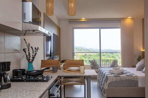 A modern kitchen with a dining area, a large window with a view, and a bed with a view. - Santa Marta Vista Mar Playa Privada (Santa Marta)