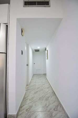 A hallway with a marble floor, a door at the end, and a vent on the ceiling. - Margarita vista al mar Piscina y La Vela (Porlamar)