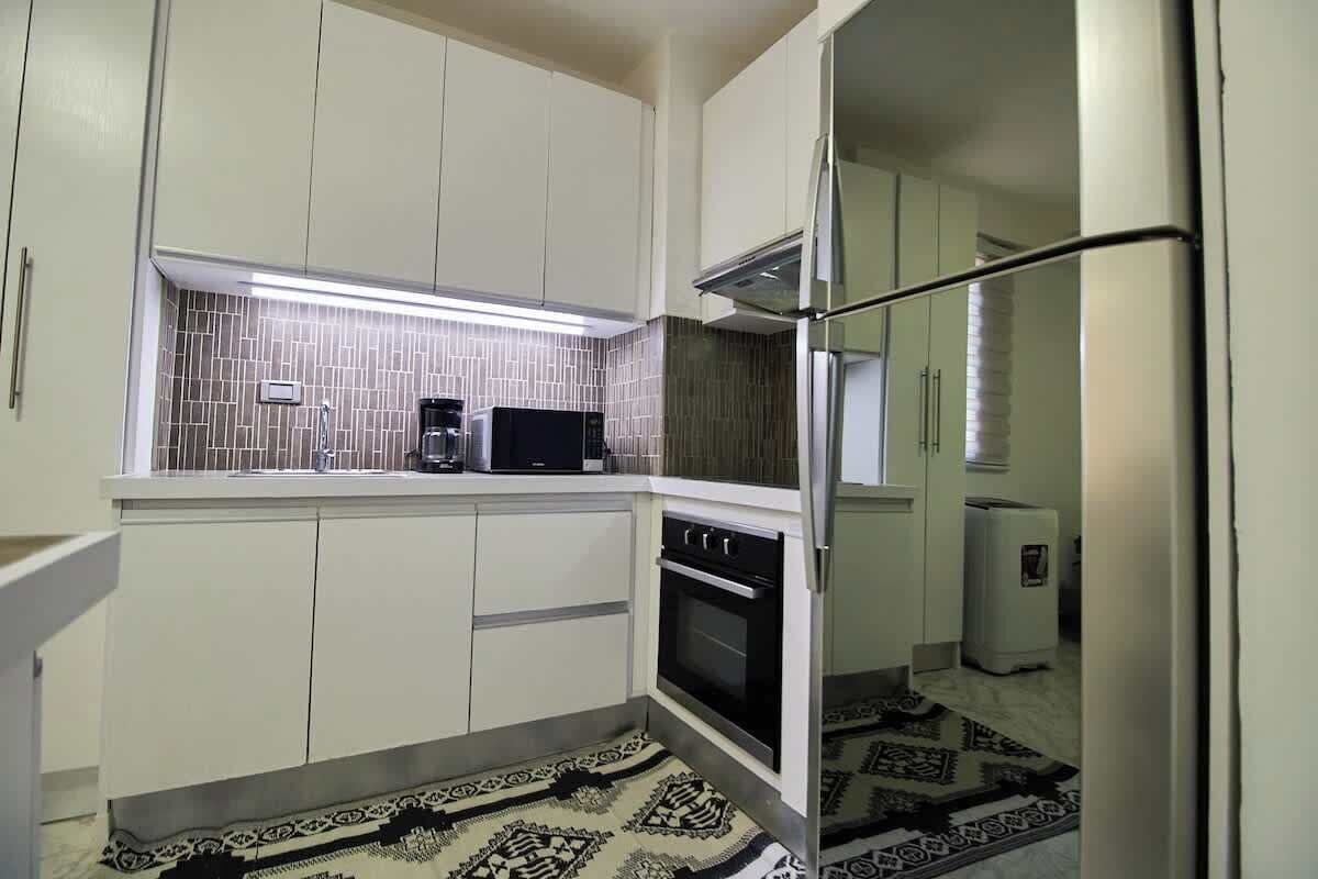 A compact kitchen with white cabinets, a microwave, a stove, and a refrigerator.