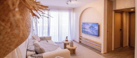 Un salon moderne avec un canapé, un téléviseur et un plancher en bois.