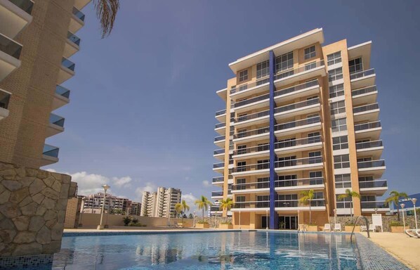 Un hotel a più piani con piscina, balconi e cielo sereno.