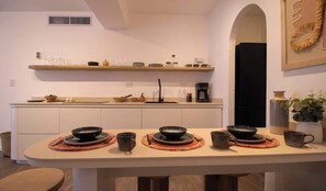 Una cucina moderna con un'isola centrale, scaffali a incasso sopra e una macchina per il caffè.