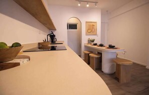 Eine moderne Küche mit einer gewölbten Arbeitsplatte, Holzbarhocker und einem kleinen Essbereich.