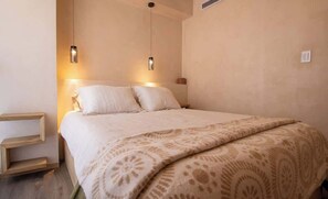 Una camera da letto con un letto, due comodini e lampade a sospensione.