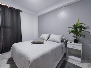 A bedroom with a bed, bedside table, and a potted plant. - Tus vacaciones perfectas a 360° (Porlamar Mariño)