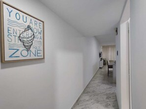 Ein Flur mit einem gerahmten Schild an der Wand, ein Essbereich mit Tisch und Stühlen sowie ein Marmorboden.