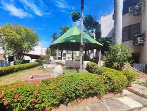 A gazebo with a green roof, surrounded by well-maintained hedges and flowering plants. - Tus vacaciones perfectas a 360° (Porlamar Mariño)