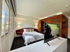 A hotel room with a bed, a TV on a stand, a wardrobe, and a window with blinds. - Encanto Clásico en Altamira: Piso 4 con Balcón (Caracas)