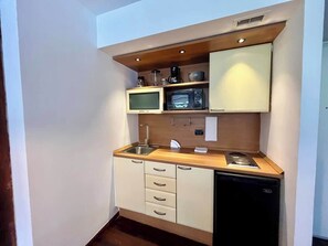 Une petite cuisine équipée d’un four à micro-ondes, d’une cuisinière, d’un évier et d’un lave-vaisselle.