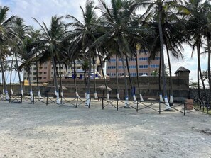 A beach with palm trees and a building in the background.