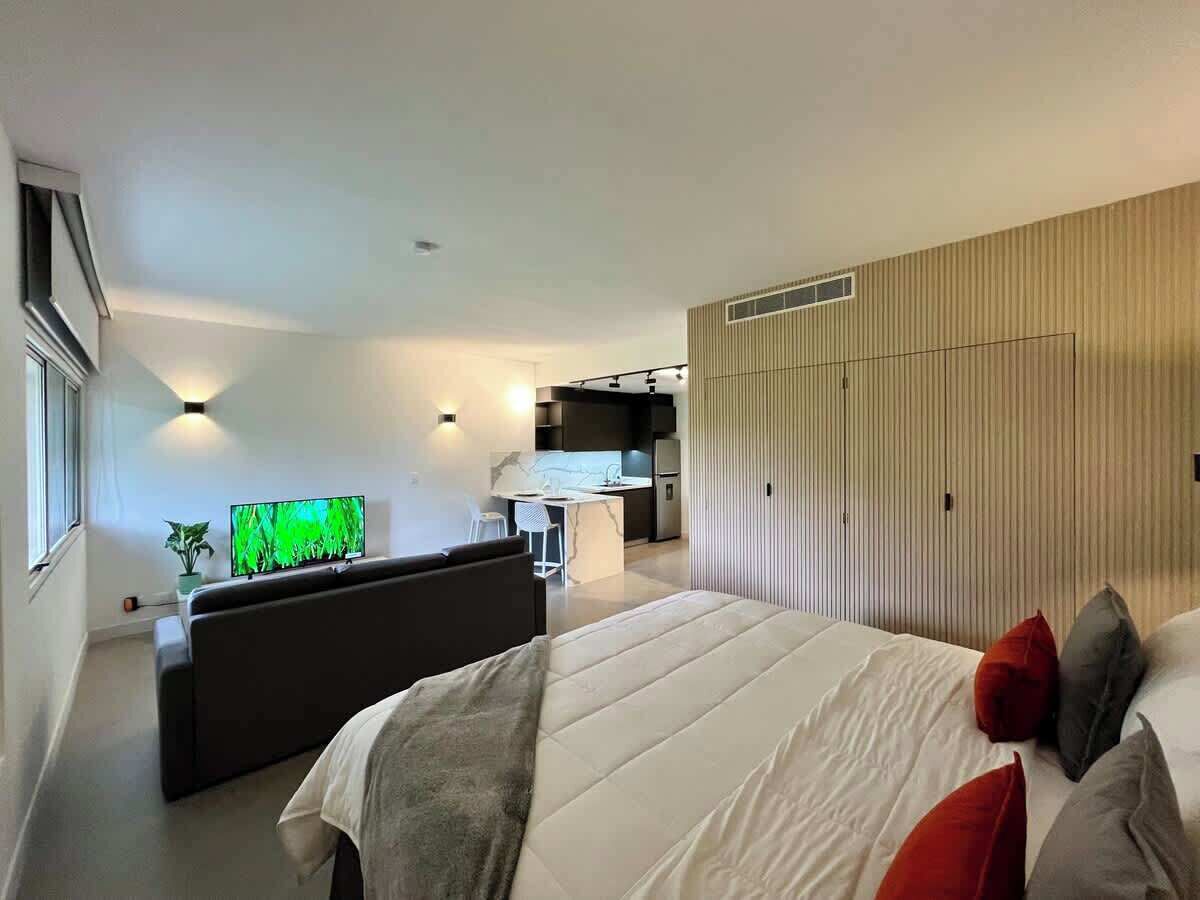 Ein modernes Hotelzimmer mit einem großen Bett, einem Schreibtisch und einer Küchenzeile.