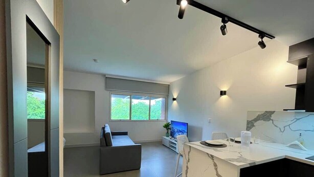 Et moderne køkken med en marmorbordplade, et spiseområde med en hvid stol og en grå sofa.