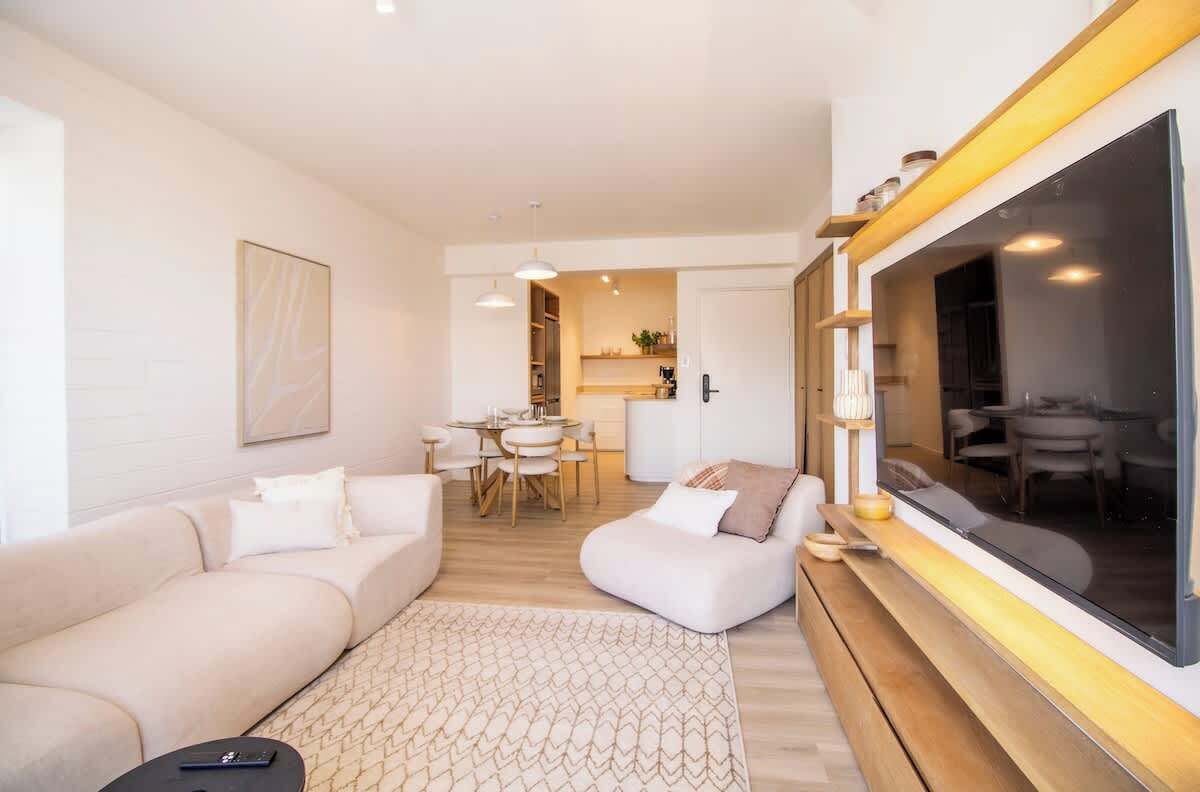 Una sala moderna con un sofá modular, una zona de comedor y un ventanal grande.
