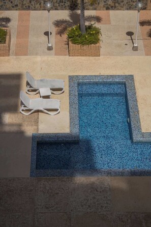 Ein Poolbereich mit Liegestühlen und einer gefliesten Terrasse.