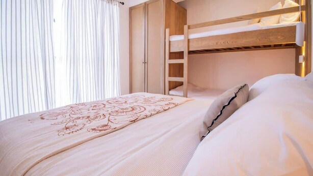 A bunk bed with a ladder, a wardrobe, and a bed with a patterned bedspread.