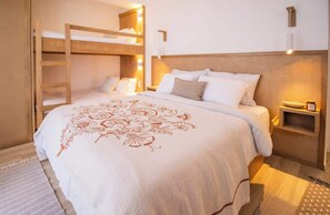A bunk bed room with a wooden ladder, a bedside table with a lamp, and a decorative bedspread. - Apartamento para 6 cerca a La Vela | Costa del Mar (Pampatar)