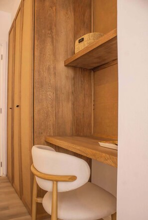 A room with a wooden wardrobe, a white chair, and a wooden shelf with a basket labeled 'HOME'. - Apartamento para 6 cerca a La Vela | Costa del Mar (Pampatar)
