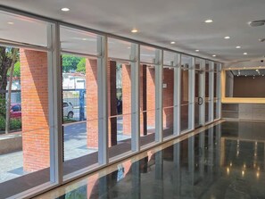 A corridor with glass doors and brick pillars, leading to an outdoor parking area.