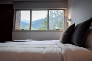 A bed with a view of mountains through a window.