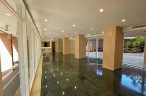A spacious lobby with a polished floor, large windows, and a wooden column. - Tu Rincón Altamira - Nomad Suites (Caracas)