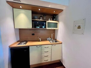 Eine kleine Küche mit Mikrowelle, Spüle und Kühlschrank.