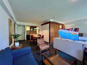 Ein Hotelzimmer mit Wohnbereich, einem Esstisch, einem Fernseher und einer Küchenzeile.