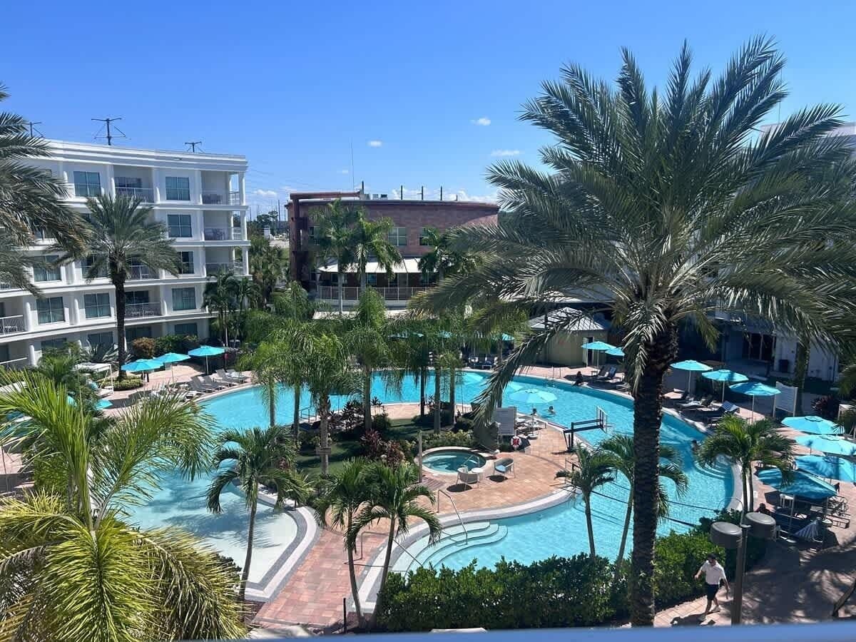 A pool area with multiple swimming pools, palm trees, and lounge chairs.