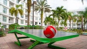 A green ping pong table with a red and white ball in an outdoor setting. - 2BR Pool View Suite Near Walt Disney World Resort (Kissimmee)