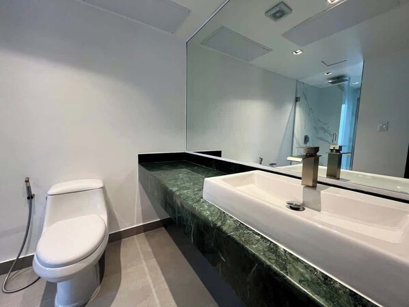 Un baño moderno con inodoro, lavamanos y un espejo grande.