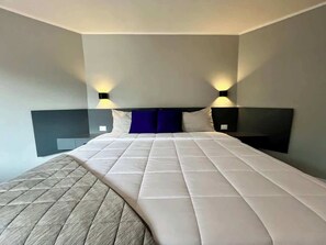 A hotel room with a large bed, two bedside tables, and wall-mounted lighting. - Moderno Ph en Altamira con hermosa vista al Ávila (Caracas)