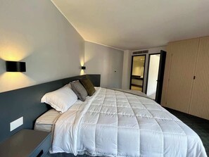 A hotel room with a large bed, bedside tables, a nightstand, and a wardrobe. - Moderno Ph en Altamira con hermosa vista al Ávila (Caracas)
