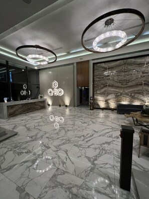 A modern lobby with marble flooring, a reception desk, and two large circular light fixtures.