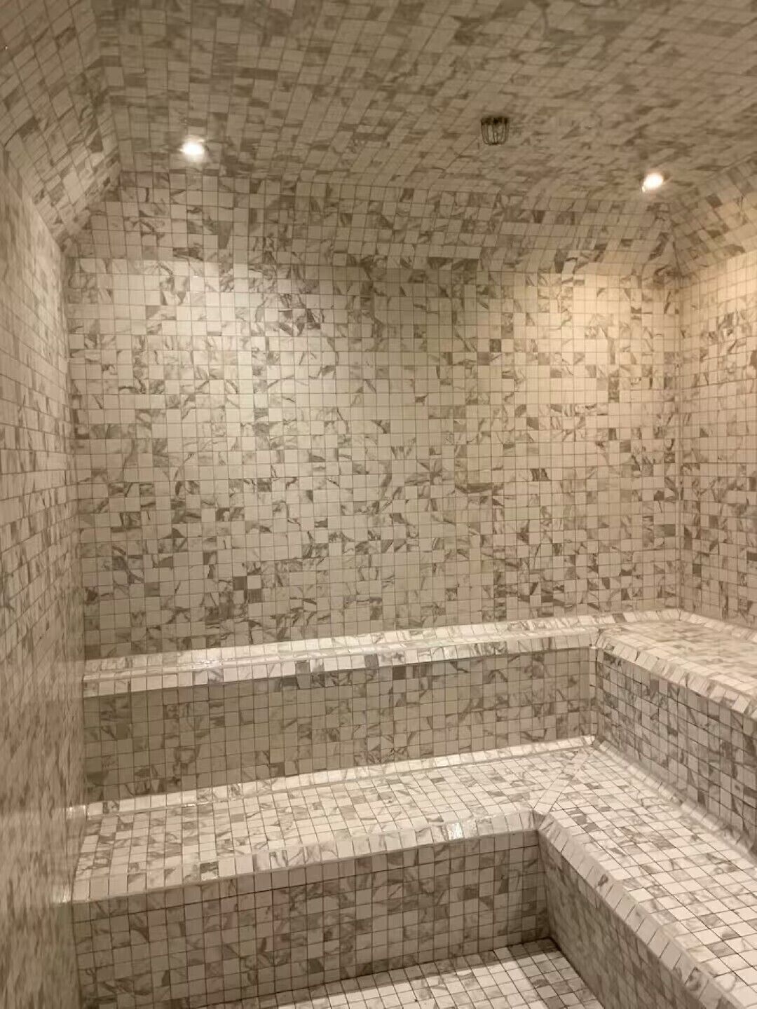 Une salle de bain avec un sol et des murs carrelés, une baignoire et un espace douche.