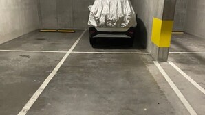 Eine Parkgarage mit einem Auto, das mit einer weißen Plane abgedeckt ist, Betonwänden und einem Boden mit der Nummer 238.