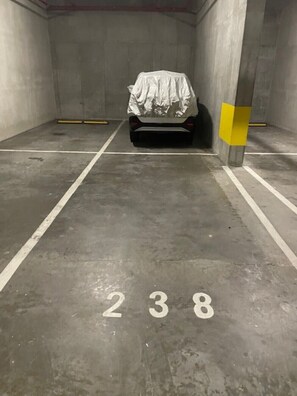 Eine Parkgarage mit einem Auto, das mit einer weißen Plane abgedeckt ist, Betonwänden und einem Boden mit der Nummer 238.