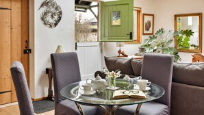 Uma sala de estar acolhedora com uma mesa de vidro, assentos confortáveis e vista para o exterior.
