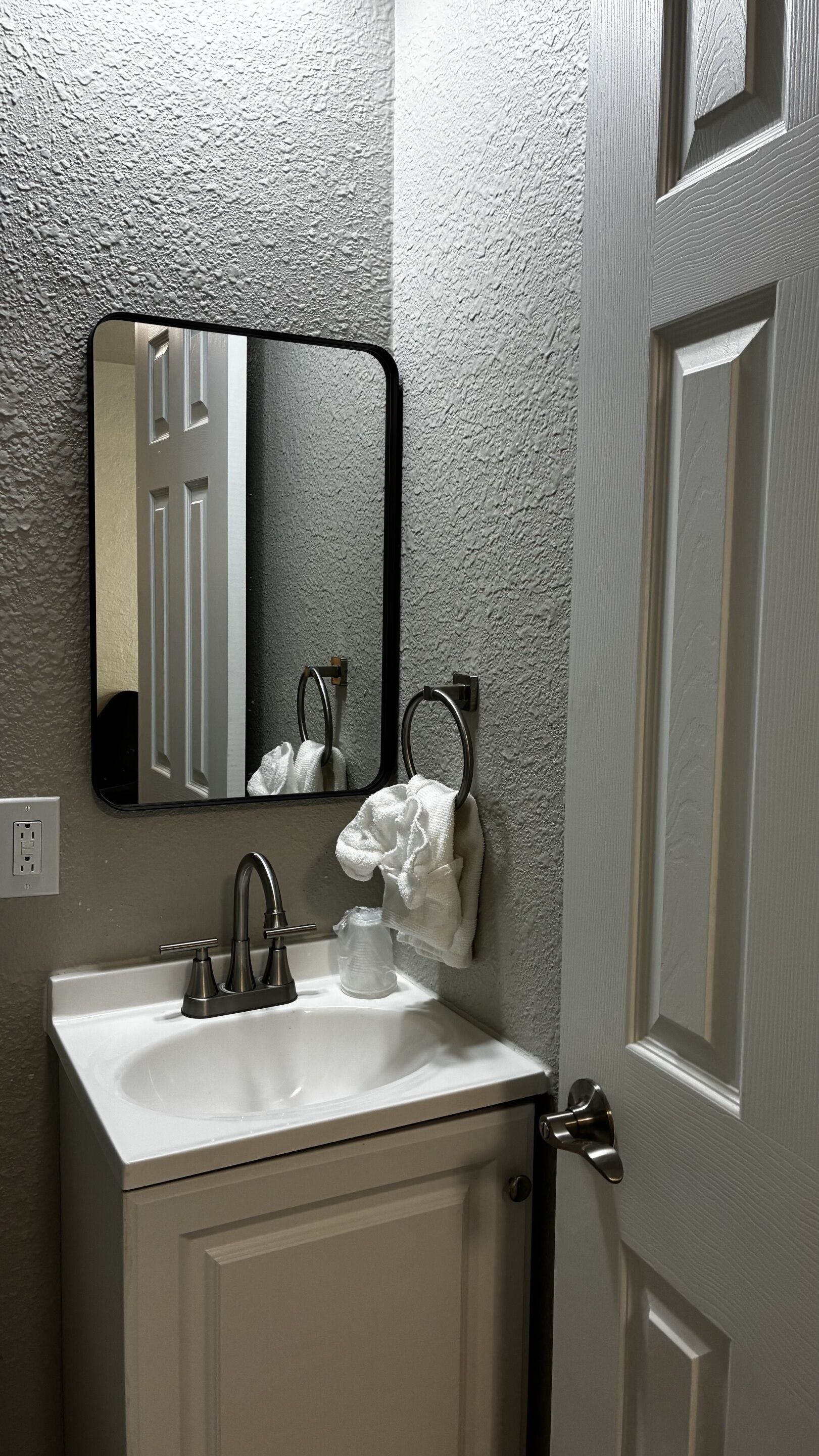 A bathroom with a white sink, a mirror, and a towel rack.