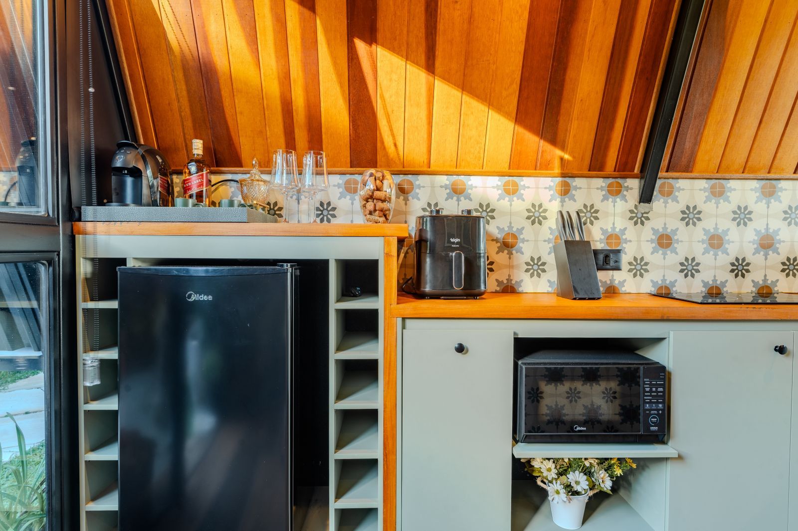 Cocina compacta equipada con refrigerador, microondas, cafetera y un lavamanos pequeño.