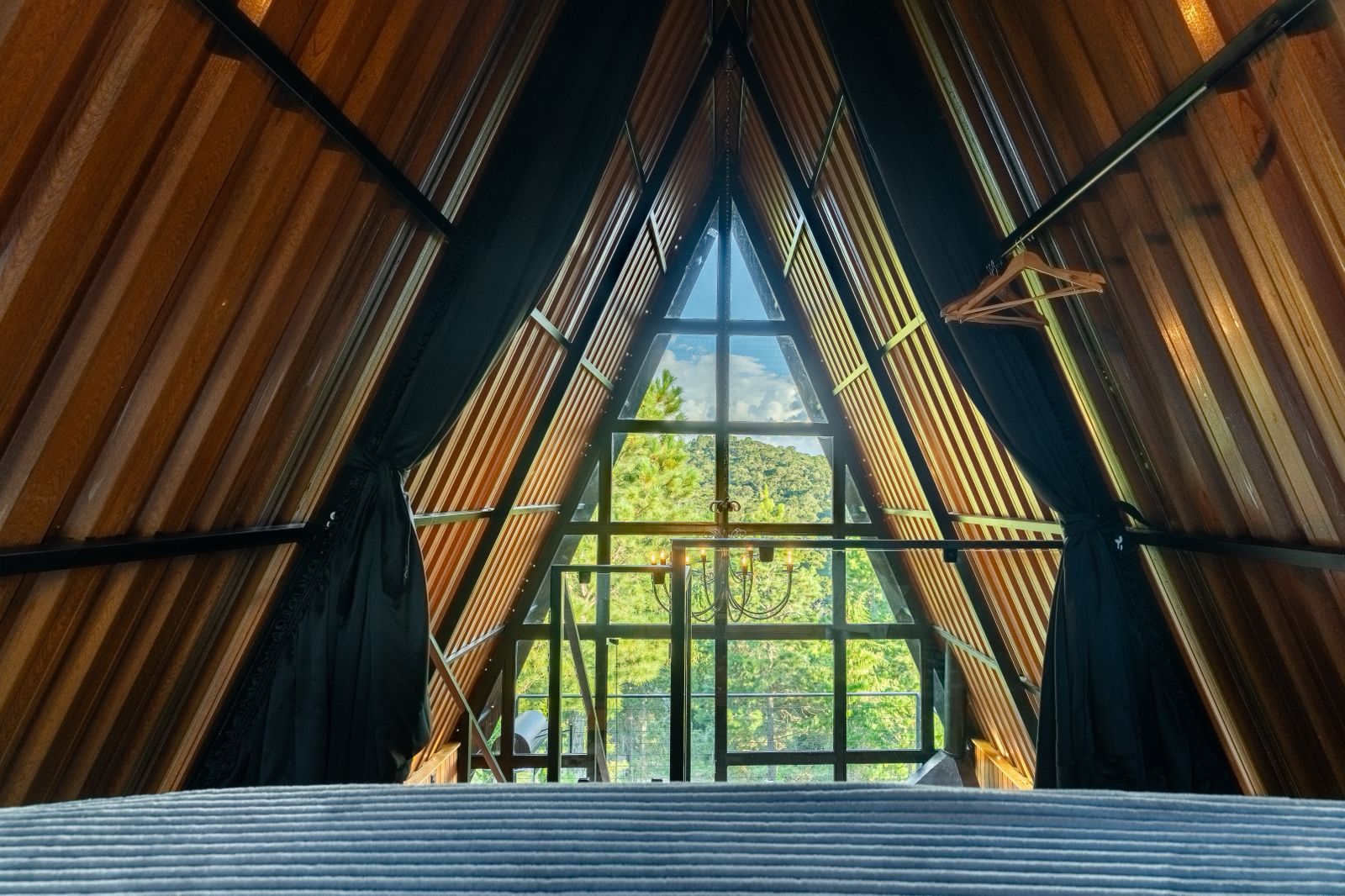 A room with a sloped ceiling and large windows offering a view of a forested landscape.