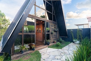 Una casa moderna con fachada de vidrio, interior de madera y un camino de piedra que lleva a la entrada.