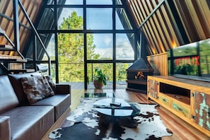 Un interior moderno con techo de vidrio, un sofá de cuero, una mesa de centro de vidrio, un mueble de madera y una chimenea.